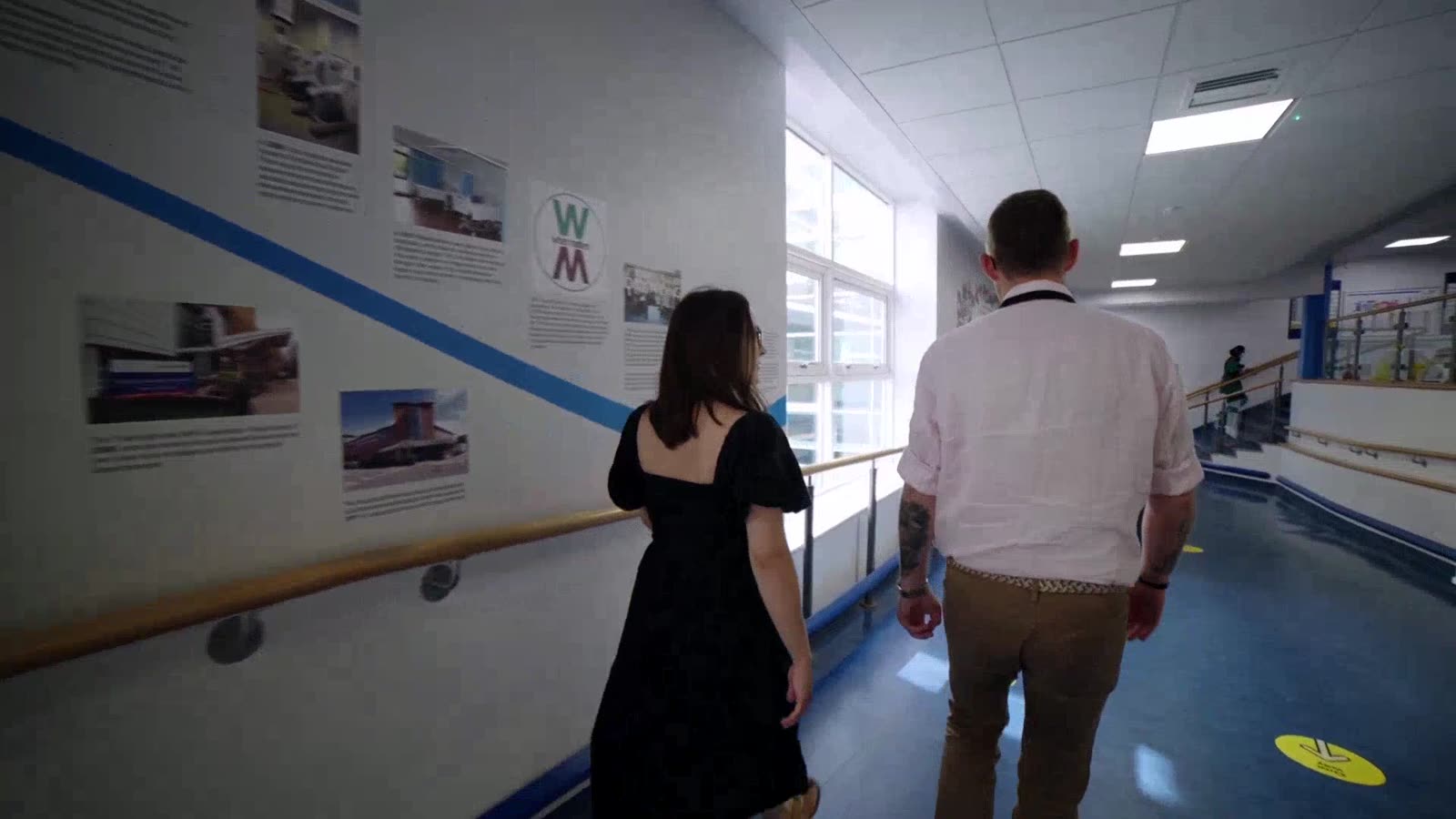 Two people walking through a hospital corridor